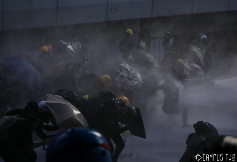 面對水砲車的攻擊，現場的港民只能趕緊開傘保護自己。   圖：翻攝自香港大學學生會校園電視臉書