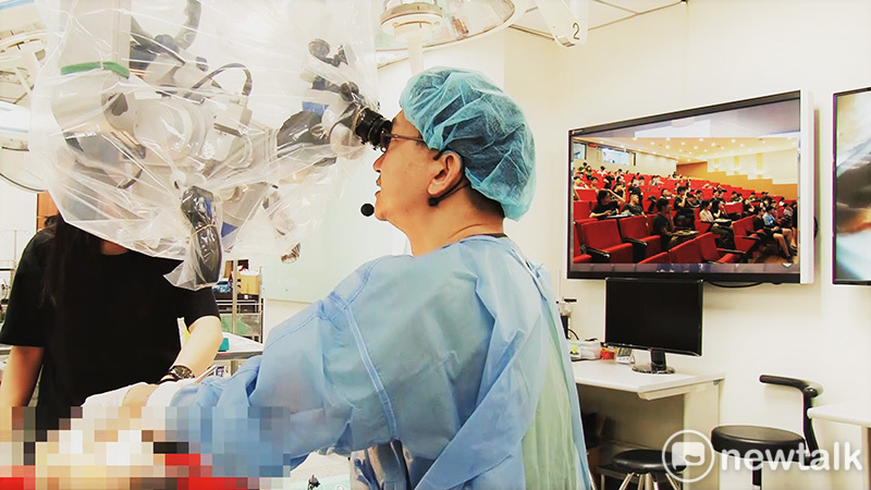 李榮順醫師在創新教室遠端連線模擬臨床手術進行大體解剖，並透過顯微鏡操作，運用遠端連線與醫學系學生互動。   圖 : 成大醫學院/提供