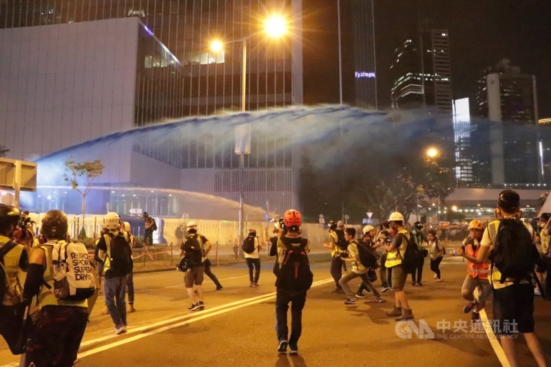 香港示威者28日晚間朝政府總部投擲汽油彈，港警於8時42分出動水炮車噴射藍色水柱及胡椒水。   圖／中央社