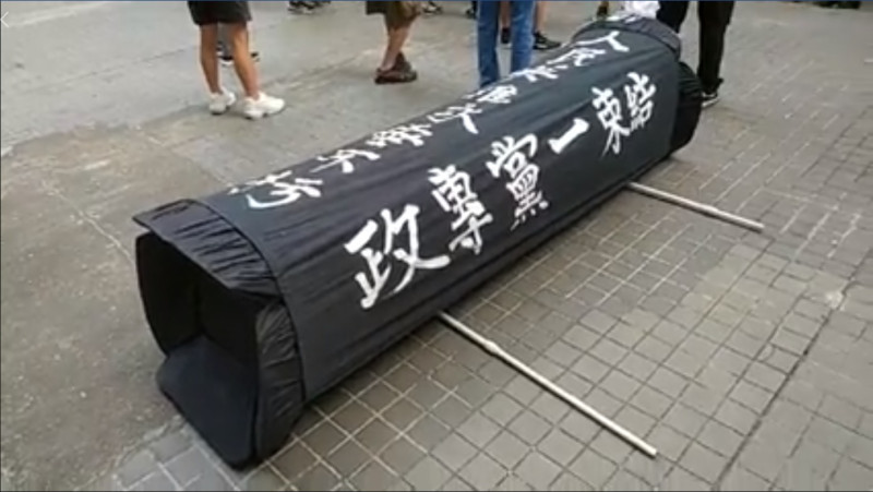 香港社會民主連線今早在灣仔發動黑衣遊行，還帶了一副「道具棺材」，遭大批黑社會襲擊，並暴力將道具棺材摧毀。   圖：翻攝社會民主連線