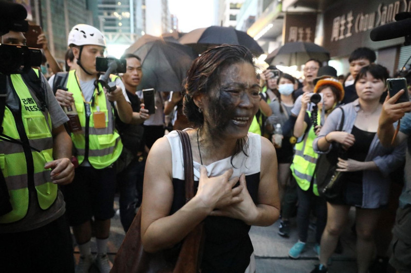 一名女士在旺角搬開路障，遭到示威者潑水，臉上噴黑漆。   圖：擷取自香港01