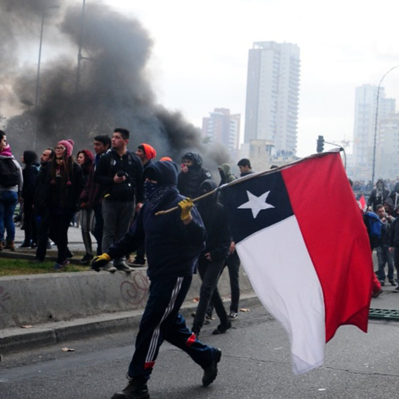 智利爆發民眾激烈抗爭，多處遭到縱火，還有人拿著反製的智利國旗示威遊行。   圖：翻攝自反帝國主義ANTICONQUISTA推特