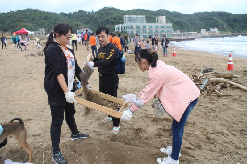 民眾利用篩網篩除沙灘中的細小垃圾。    圖：新北市環保局提供