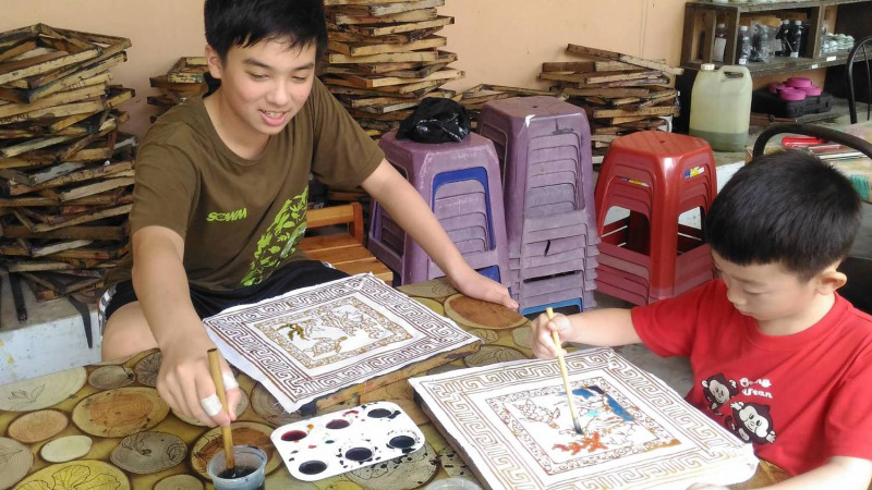 黃家融同學(左一)和小表弟一起彩繪馬來西亞手工藝峇迪。   圖：移民署提供