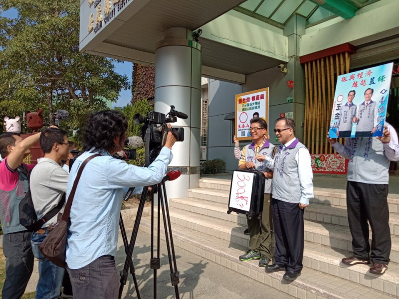 台灣維新黨立委候選人王金山帶著一只寫著「300萬？」的皮箱前往登記。   圖：王金山競選團隊/提供