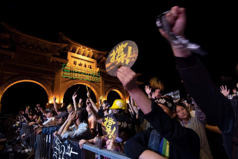「自由香港」雷射光投射在自由廣場牌樓，眾人手舉「撐」標語，頭綁「香港加油」聲援香港。   圖：守民主護台灣大聯盟/提供