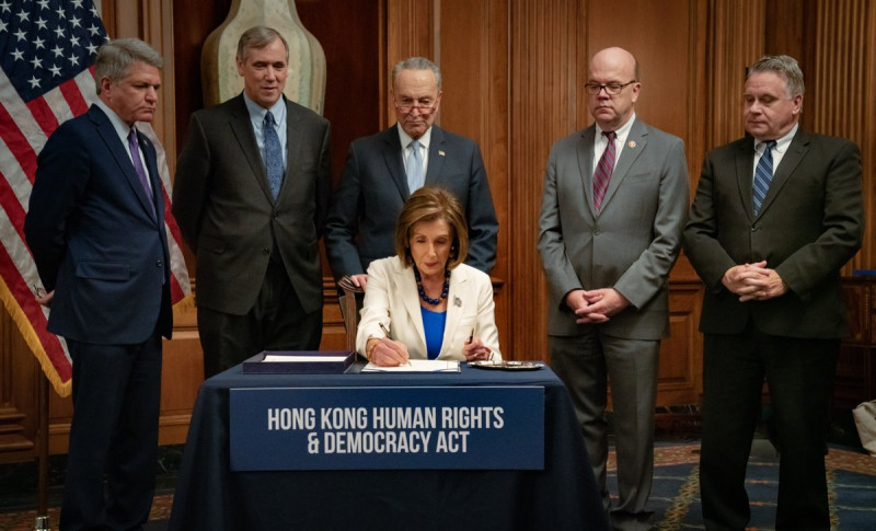 美國眾議院議長斐洛西（前坐者）火速簽署表決通過的參院版《香港人權與民主法案》，交給白宮。   圖：翻攝自斐洛西推特