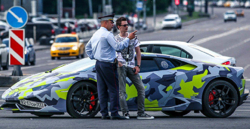 俄羅斯駭客雅庫貝斯（右）駕駛藍寶堅尼跑車在街頭被拍到，可惜與他交談的交通警察沒能認出他來。   圖：翻攝自英國國家犯罪局