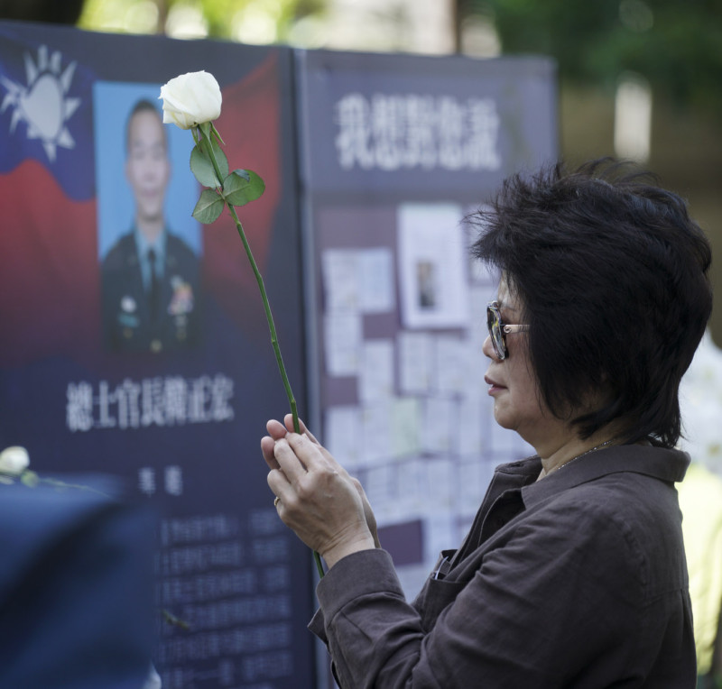 一位媽媽手持白色獻花，向殉職將士的肖像鞠躬。   圖：張良一 /攝