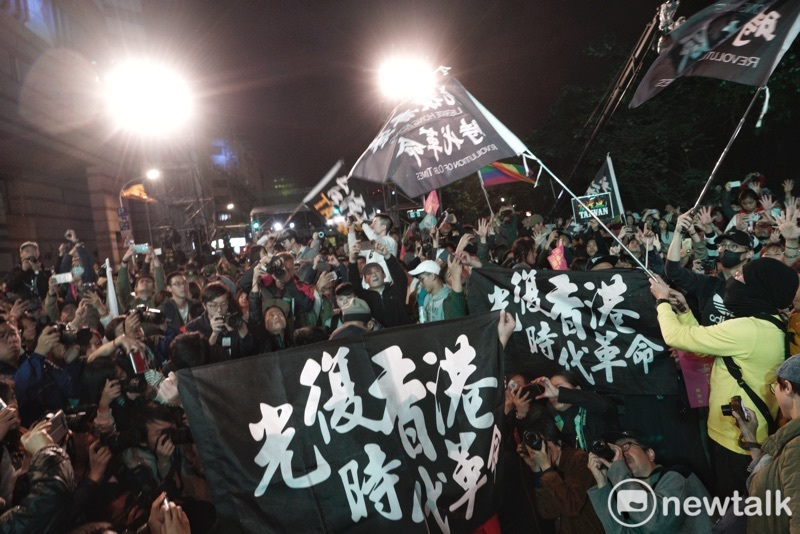 數十位在小英競總外見證台灣民主自由的香港人在現場揮舞或是高舉「光復香港時代革命」旗幟後，並以不曝光方式比出五大訴求手勢。   圖：張良一/攝