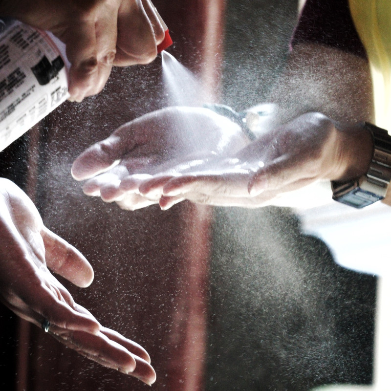 艋舺龍山寺的一位保全人員為香客的雙手噴上殺菌液。   圖：張良一/攝