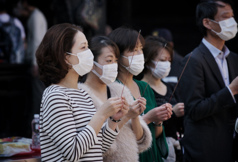 來自日本的觀光客戴上口罩向艋舺龍山寺的觀音佛祖獻上一柱馨香。   圖：張良一/攝