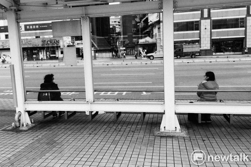 兩位民眾在台北車站等公車時，刻意拉開距離。   圖：張良一/攝