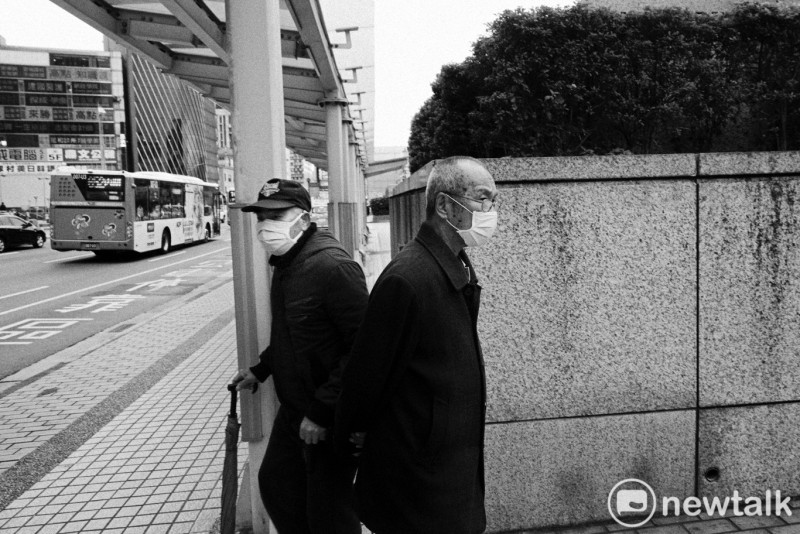 兩位戴著口罩的老伯伯在台北車站前等公車。   圖：張良一/攝