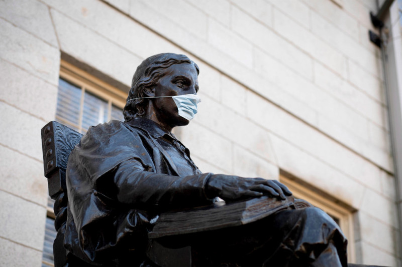 哈佛校園知名的約翰哈佛雕像，也被人戴上了口罩。   圖：翻攝自twitter.com/harvard