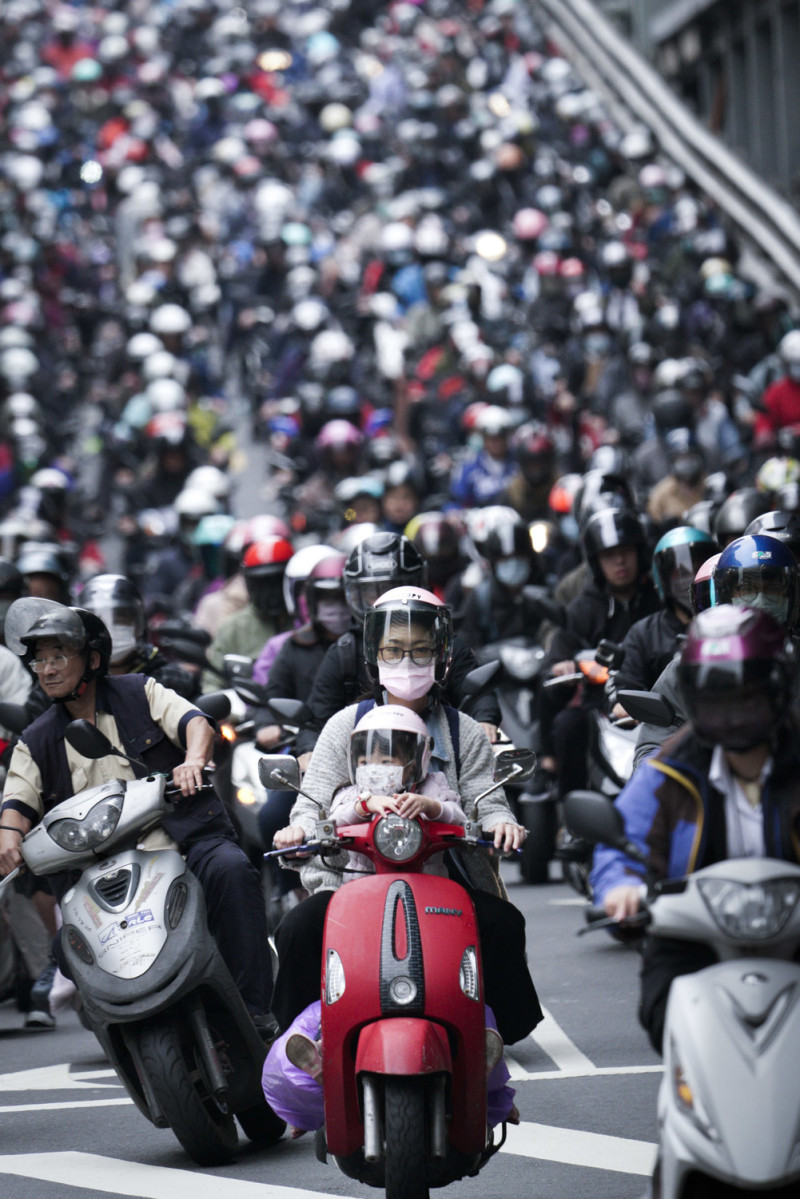 週一清晨，數以千位民眾騎著機車，從新北市經台北橋到台北市上班、上課。受疫情影響，幾乎所有的騎士都戴上口罩。   圖：張良一/攝