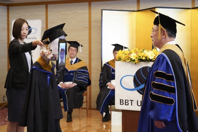 學生可遠端操控分身機器人，「親手」拿到畢業證書，並跟校長合影。   圖：翻攝自BBT大學官網
