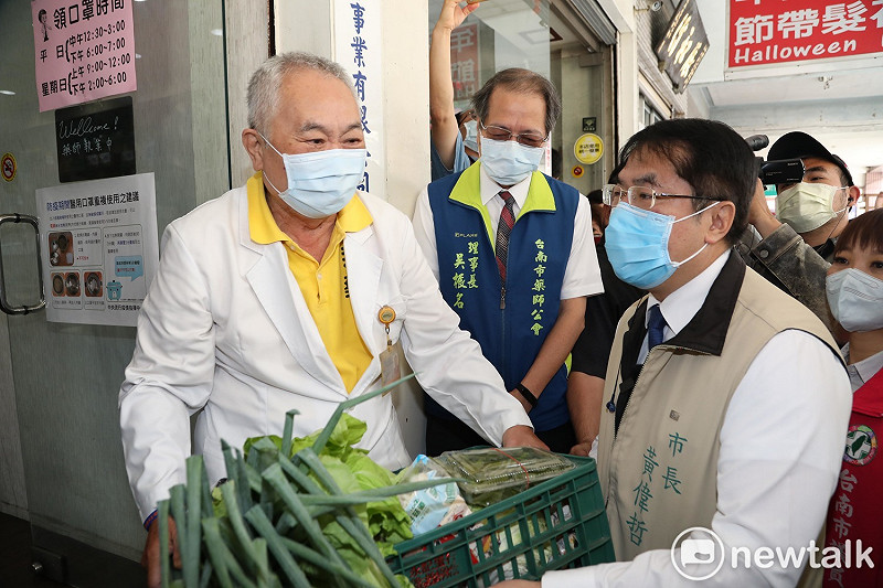 台南市長黃偉哲化身外送員，帶著在地新鮮食材前往「千代藥局」，慰勞高齡72歲的老藥師陳盈舟。   圖：黃博郎／攝