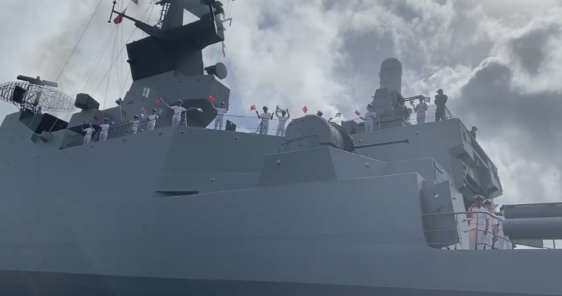 艦隊離開帛琉時，船上官兵揮舞國旗向帛琉民眾說再見，但大部分的人疑似均未配戴口罩。   圖：翻攝自周民淦臉書