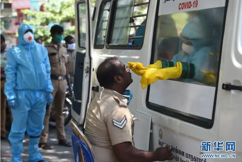 穿著防護裝備的印度醫務人員為警察進行武漢肺炎檢測。   圖：翻攝自新華網