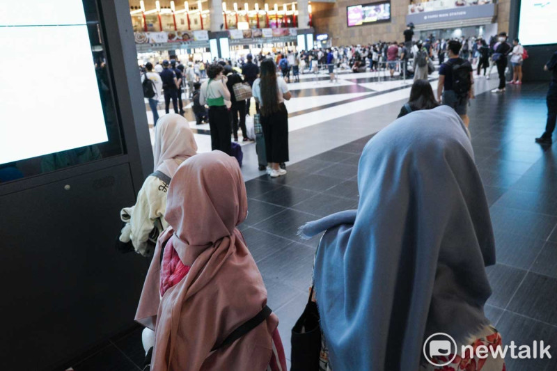 一些來自印尼的穆斯林移工在台北車站大廳的角落，看著在大廳正中央唱歌跳舞的台灣年輕人。他們知道台鐵之前打算永遠禁止在車站大廳席地而坐的新聞。   圖：張良一/攝