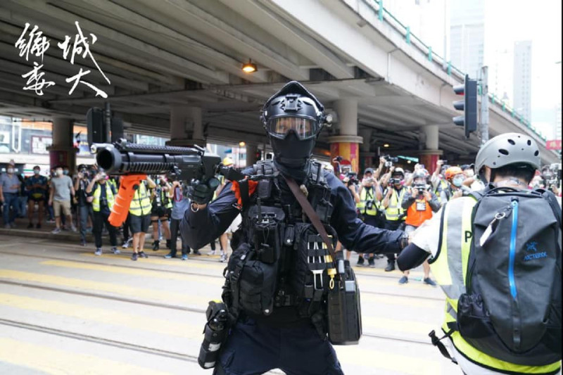 有一名警員以胡椒球槍近距離直指在場記者，但記者群身後的市民早已散開。   圖：翻攝自香港城市大學學生會編輯委員會