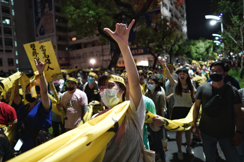 一位參加遊行的民眾在遊行中高舉罷韓手勢。   圖：張良一/攝