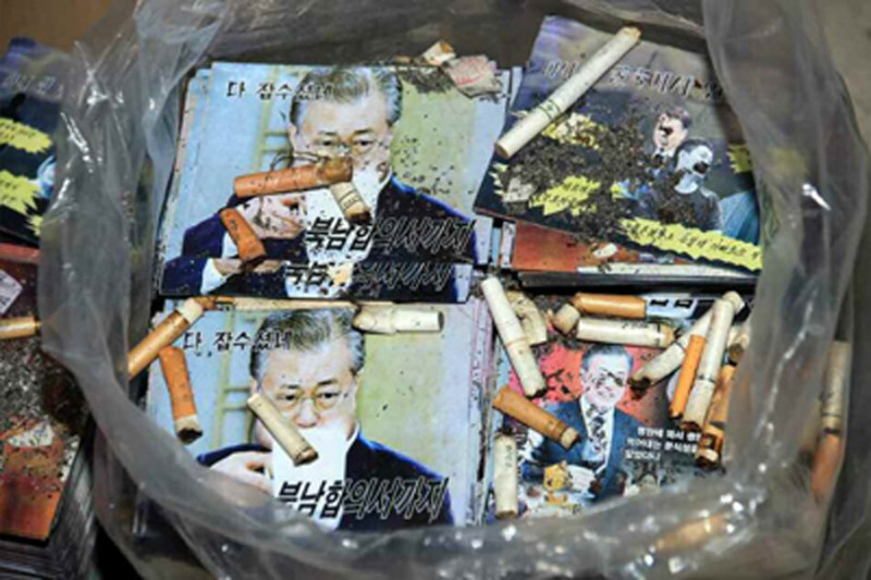 北韓工人將菸蒂丟在南韓總統文在寅肖像上。   圖：翻攝自勞動新聞網頁