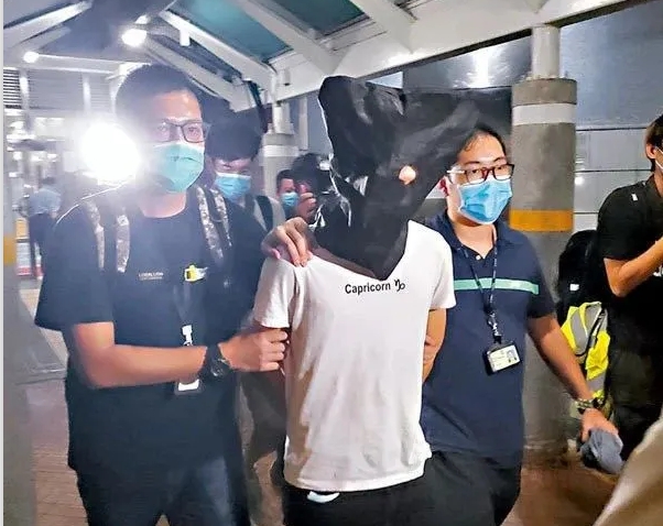 香港七一遊行刺警案的涉嫌男子，被警方帶下飛機。   圖：翻攝自北京日報