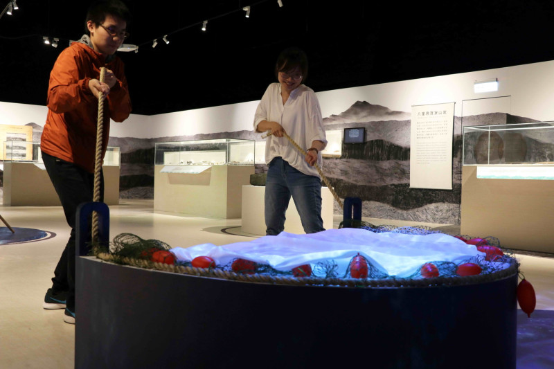 「山水八里—八里人文與自然特展」可透過牽罟互動裝置，體驗合力捕魚的樂趣。    圖：十三行博物館提供
