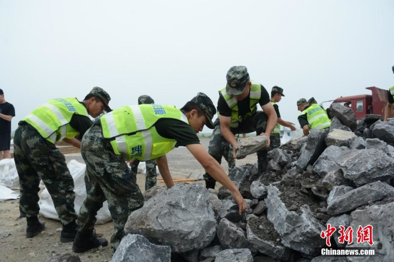 中國洪災湖北陽新出現潰堤，武警搬動石塊堵住缺口。   圖 : 翻攝自中新網