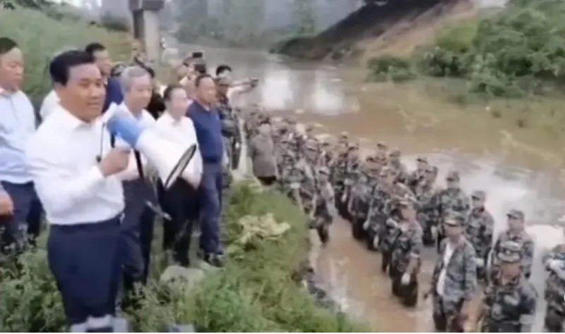 一群身穿白襯衫的人站在岸上，指揮腳踏在水裡的戰士照片近日在中國引起極大討論。   圖：翻攝自東邪洪七公微信公眾號