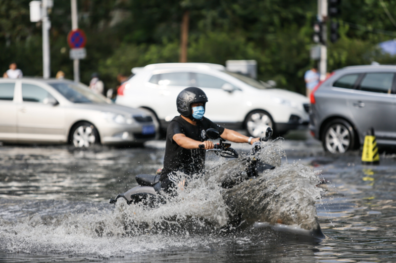 位在北京的摩托車騎士在積水中。   圖片來源：視覺中國圖