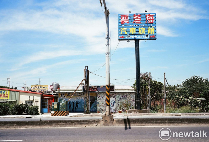 在城市邊緣，巨大的廣告看板、常見的鐵皮屋，70年代的台灣經濟發展模式受到多少的美國影響?這是余白的影像創作計畫所要提出的疑問。    圖：余白攝影/提供