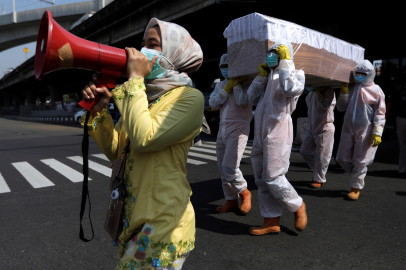 印尼雅加達政府官員親自穿上整套防護裝備每天在街頭「抬棺」，希望民眾正視新冠肺炎帶來的威脅。   圖：達志影像／路透社