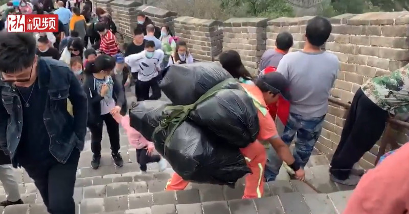 中國八達嶺長城景區的清潔人員身背兩三大袋垃圾在陡峭的長城清理遊客亂丟的垃圾。   圖：翻攝浙江新聞