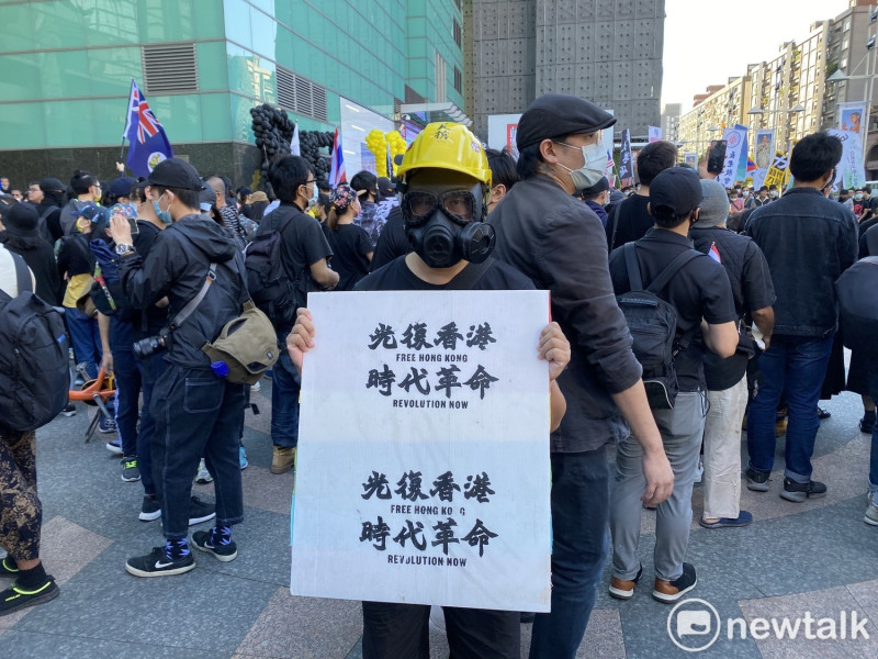 遊行民眾打扮成港人抗爭模樣，高舉「光復香港，時代革命」標語。   圖：周煊惠／攝