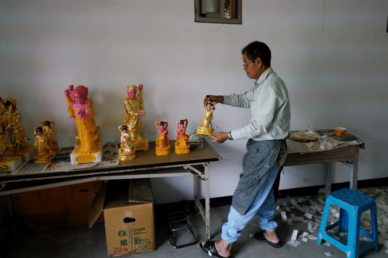 從板橋來的蔡清風先生為東莒大坪村一座廟宇的神像，重貼金箔。   圖：張良一/攝