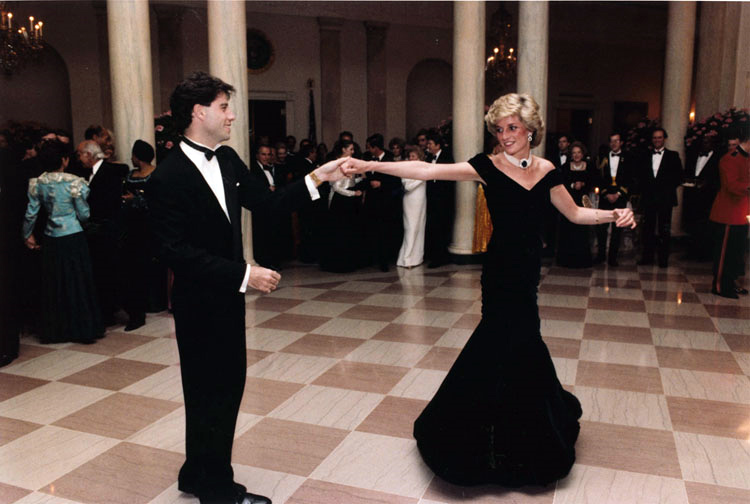 黛安娜王妃（右）自從婚姻爆出第3者後，1994年6月開始穿上這款黑色低胸緊身性感的「復仇裙」，挑戰英國王室傳統，左為好萊塢影星約翰屈伏塔。   圖：翻攝自維基網站