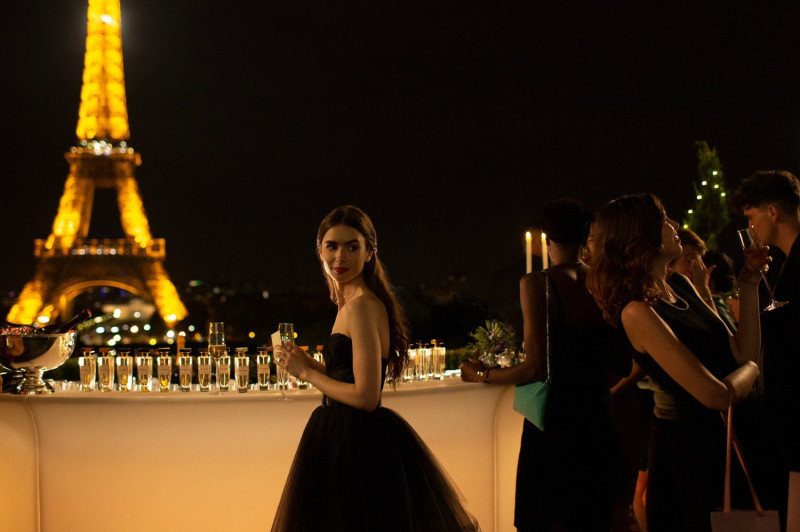 愛情喜劇影集《艾蜜莉在巴黎》取景巴黎夢幻鐵塔地標前，艾蜜莉(莉莉柯林斯 飾演)身著經典黑色小禮服亮麗登場。   圖：Netflix/提供
