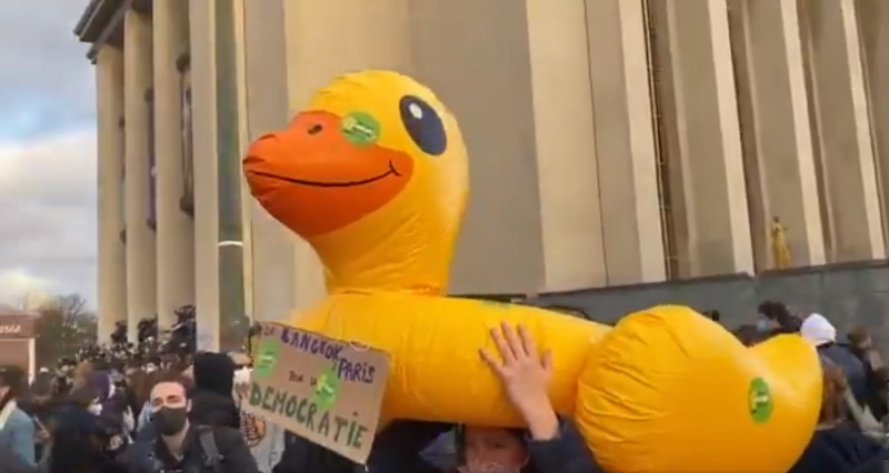 法國抗議現場有參與者拿著出現在泰國象徵民主抗爭的黃色小鴨，紙牌寫道：「從曼谷到巴黎，為了民主」。   圖/翻攝自推特