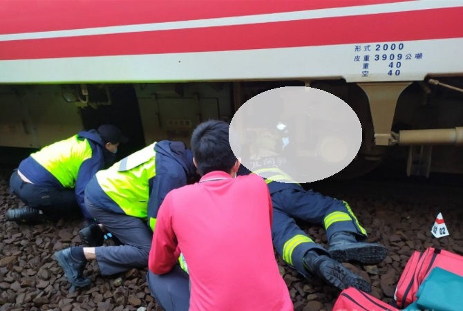 婦人墜落月台遭普悠瑪列車撞擊，警消鑽入車底搶救。   圖/宜蘭縣消防局提供