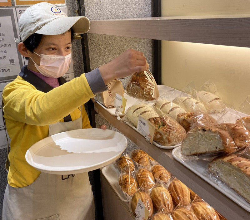 庇護員工將包裝好的麵包一一上架。    圖：新北市勞工局提供