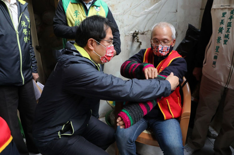 黃偉哲關心阿公保暖問題，親手為阿公穿戴防寒衣物。   圖：台南市政府提供