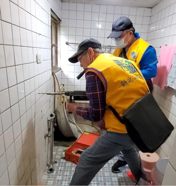 新北電器裝修業工會理事長林惠達(左)協助蕭伯伯裝設浴室扶手。   圖：新北市勞工局提供