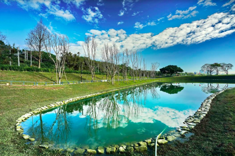 「沐心池」名稱的由來為狀似美麗的心形，池水幽靜景緻優美，池邊的大榕樹倒映著藍天是自行車騎乘停留點。   圖：新北市高灘地／提供