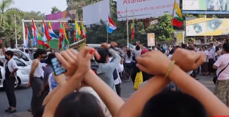 數百名軍方支持者今（25）日在仰光遊行時，揮舞著刀子、彈弓攻擊抗議的居民，婦女和兒童手挽著手試圖阻止逮捕反政變抗議者。   圖：翻攝Youtube