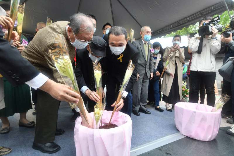 侯友宜和與會者默哀後，手執鮮花走到紀念碑前獻花。   圖：新北市政府提供