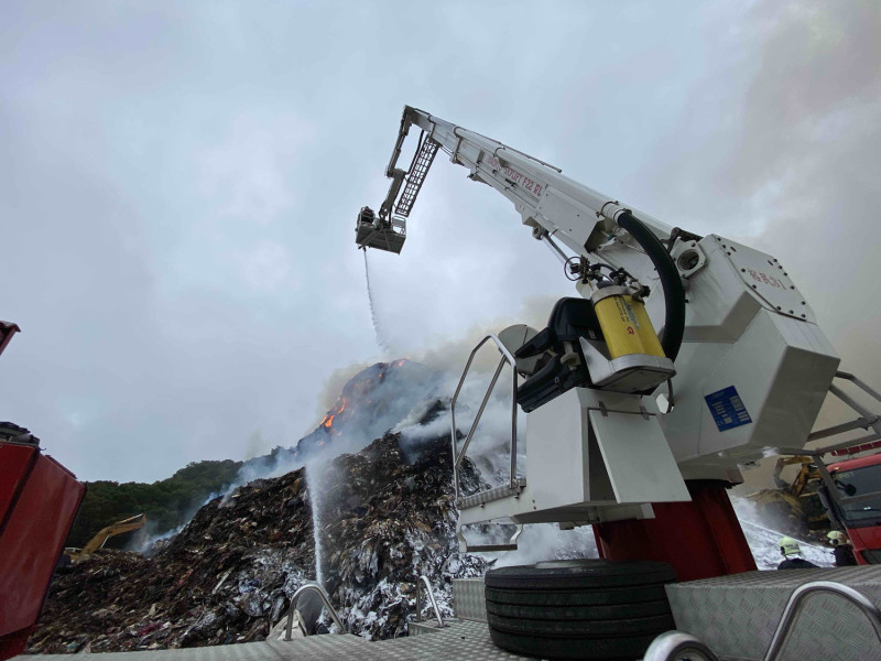 新北市環保局、消防局出動大型機械灌救八里掩埋場失火。   圖：新北市環保局提供