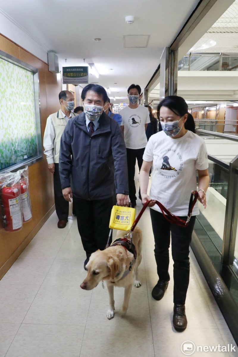 台南市長黃偉哲（前排左）特別閉著眼腈，藉由導盲犬的帶領進入會場，實際感受低視能朋友們在尋路上的不便。   圖：黃博郎／攝